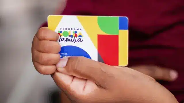 Mulher verifica o calendário de pagamento do Bolsa Família no aplicativo Caixa Tem em seu celular
