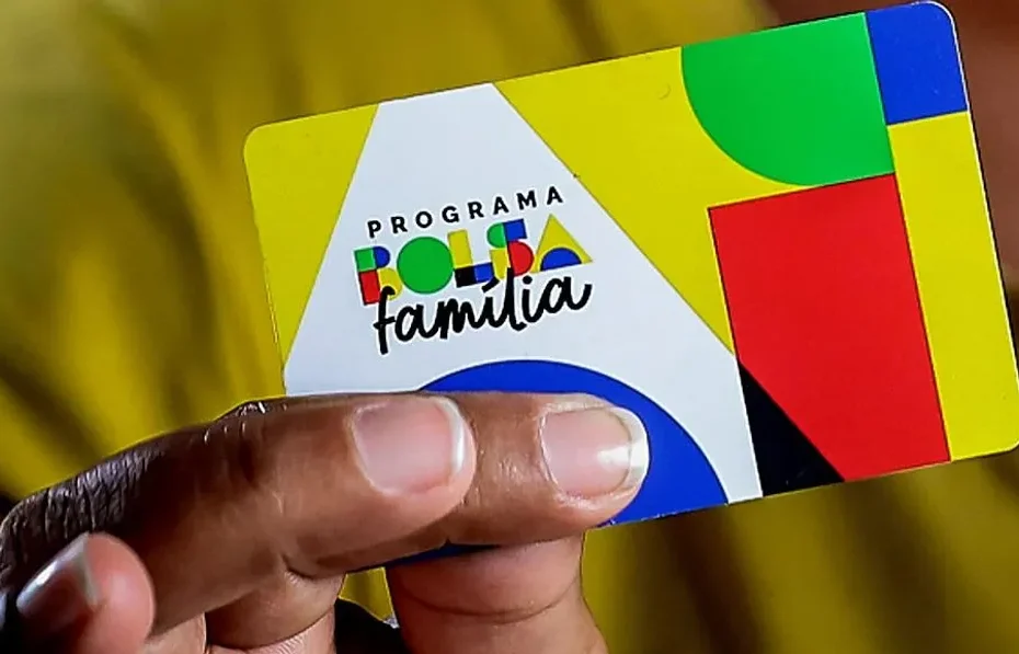 Família com pai, mãe e filho sorrindo, olhando documentos em casa, simbolizando o aumento de renda e saída do Bolsa Família.