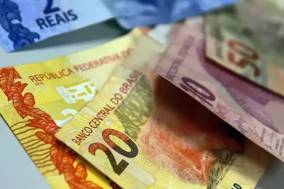 Mãos segurando cartão de benefício do INSS próximo a um celular com o aplicativo oficial
