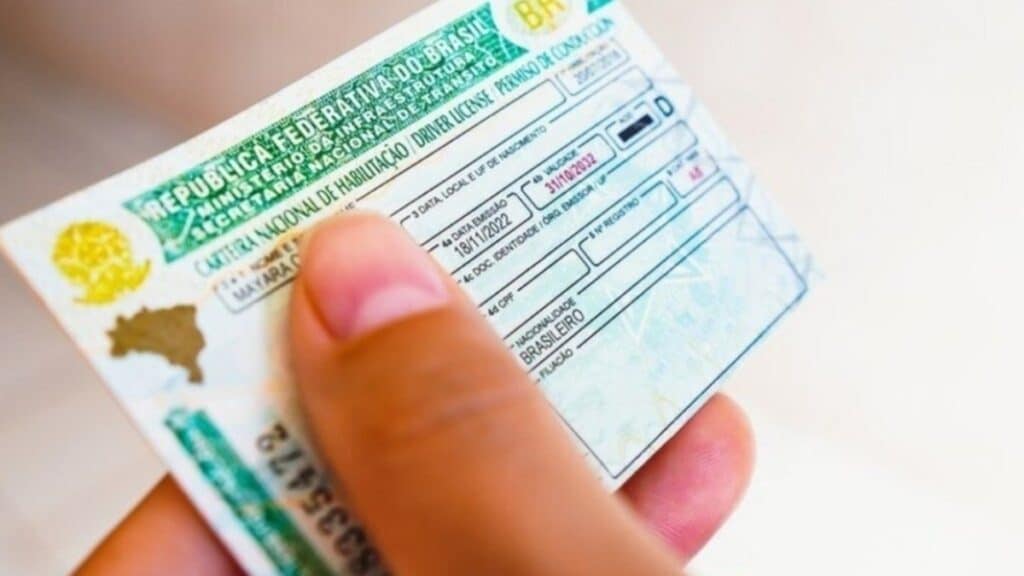 Motorista sorri aliviado ao ver extensão da validade da CNH em seu celular.