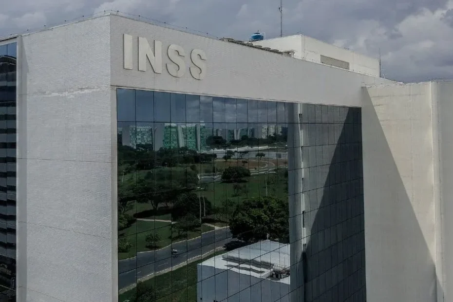 Mãos de uma pessoa idosa segurando documentos do INSS com uma fila borrada ao fundo