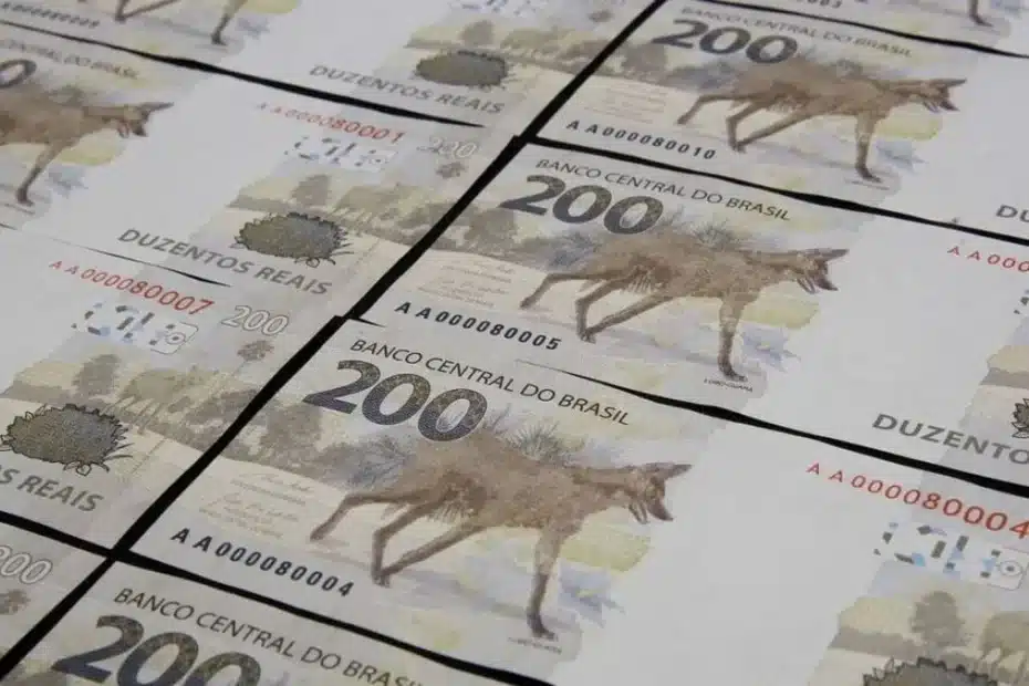 Mão segurando uma nota de R$ 200 em um ambiente de comércio, ilustrando a circulação da moeda.
