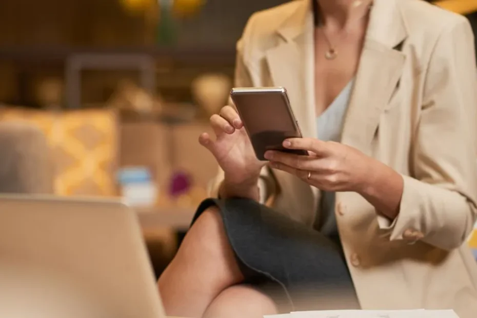 Empreendedores sorrindo em um escritório moderno, visualizando dados financeiros em tablets e laptops, celebrando a economia com uma conta PJ digital sem mensalidade.