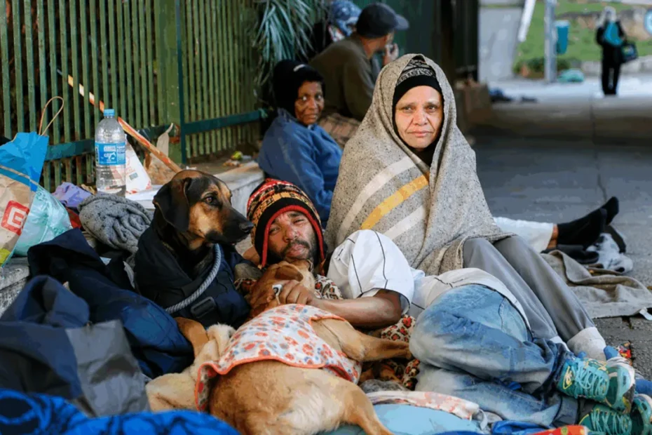 Famílias em situação de rua em São Paulo com moradias improvisadas, refletindo o aumento da vulnerabilidade e a falta de acesso a auxílios e benefícios.