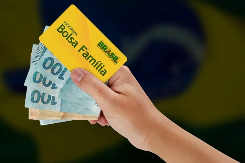 Mãos de beneficiário do Bolsa Família segurando o cartão do programa e consultando o calendário de pagamentos de agosto de 2026 no celular.