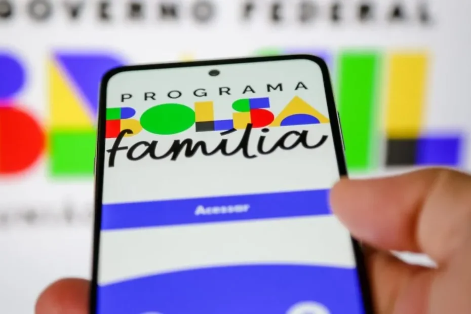 Mãos segurando celular com informações de pagamento do Bolsa Família de agosto de 2026