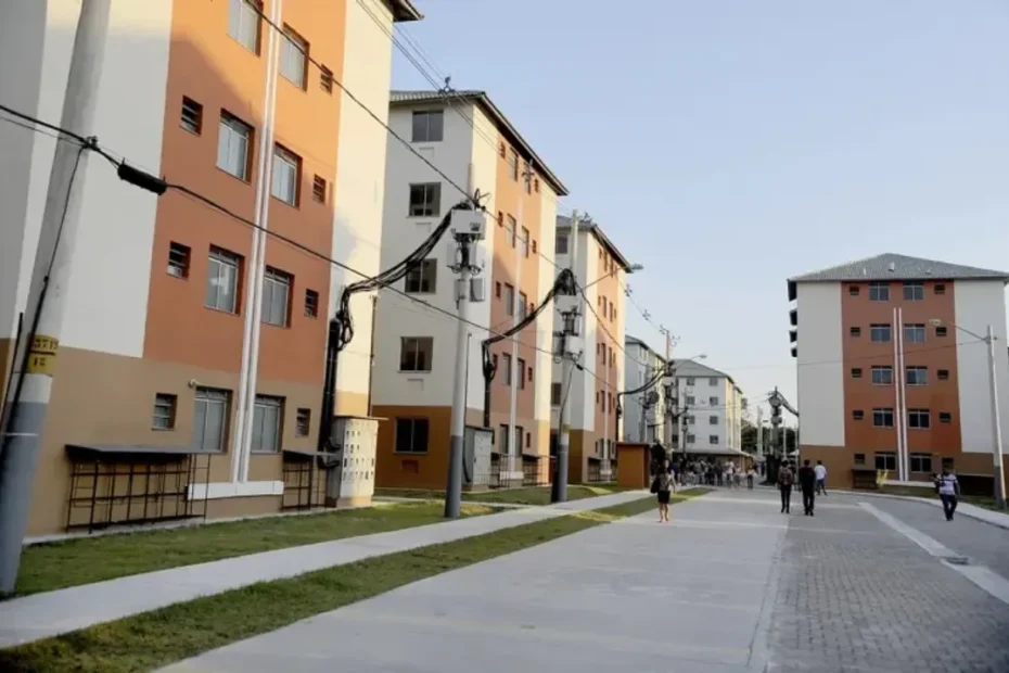 Família sorridente em frente a um novo conjunto de apartamentos do programa Minha Casa, Minha Vida em Cariacica.