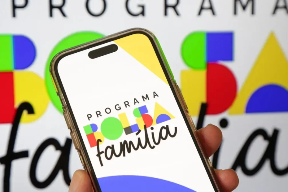 Mão de uma pessoa segurando um smartphone com o aplicativo Caixa Tem aberto, exibindo informações do Bolsa Família.