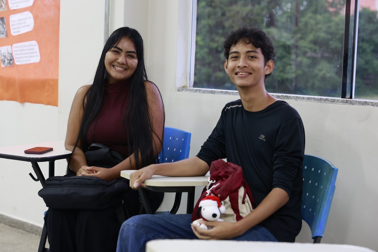 Estudantes em grupo sorrindo enquanto consultam informações sobre o Fies em um notebook.