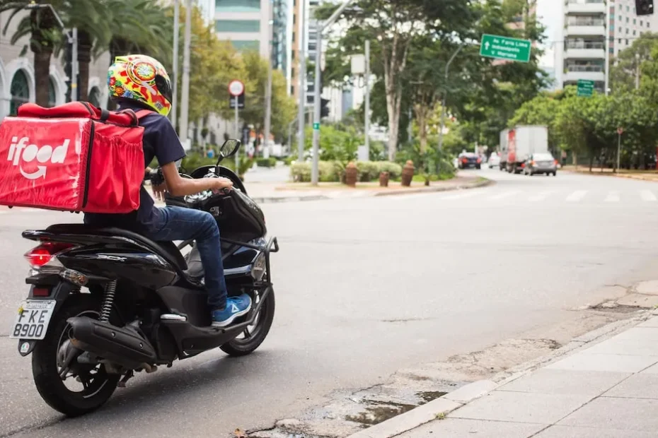Mãos de motorista de aplicativo ou entregador de comida olhando um smartphone, simbolizando o acesso a crédito e finanças.