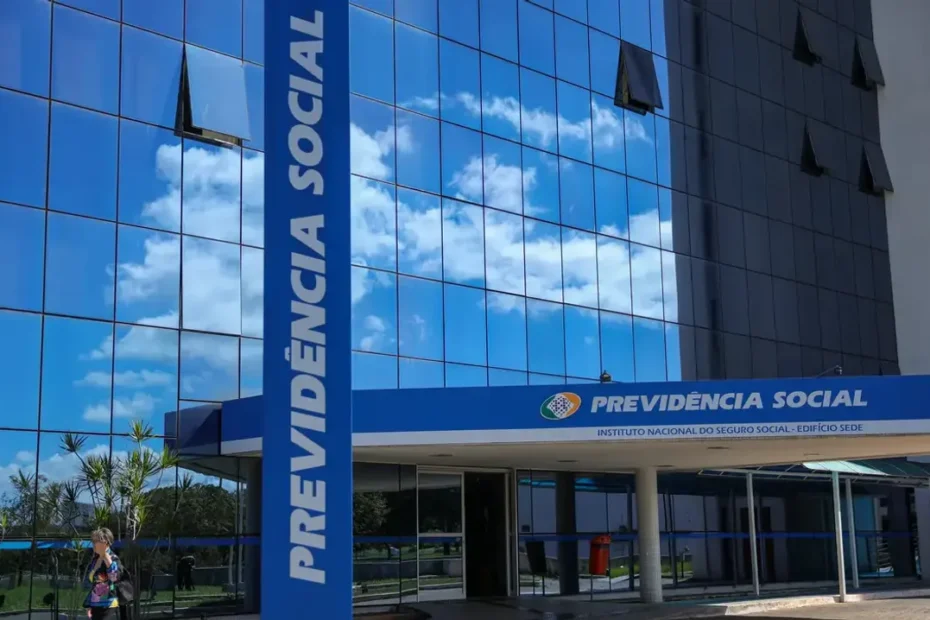 Mãos segurando documento de identificação em frente ao logo do INSS