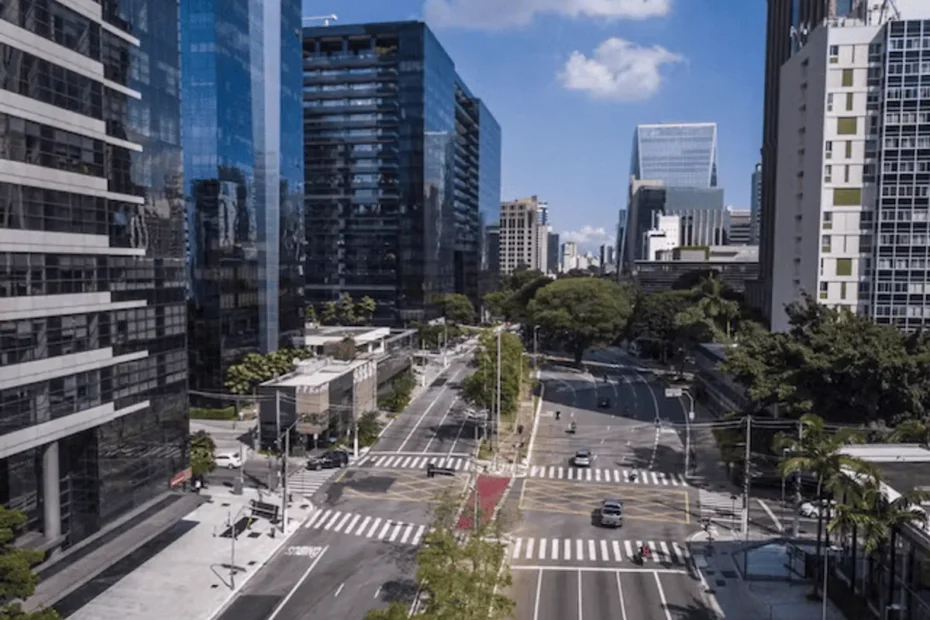 Gráfico de ações mostrando crescimento em tela, com prédios de bancos ao fundo