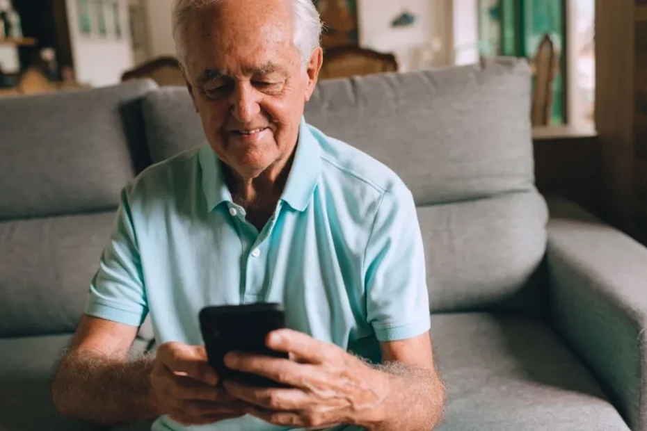 Mãos de uma pessoa idosa preenchendo o aplicativo Meu INSS em um smartphone, buscando informações sobre o BPC.