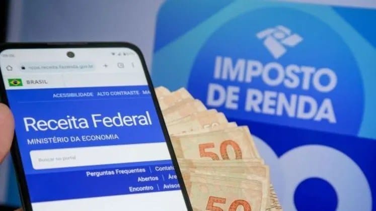 Pessoa segurando celular com tela do Pix exibindo crédito de restituição do IR
