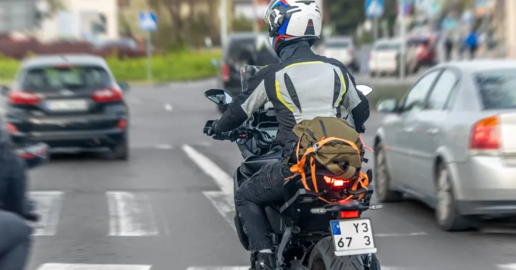 Mototaxista feliz em uniforme, segurando documentos de compra de uma motocicleta nova, simbolizando acesso a benefícios.