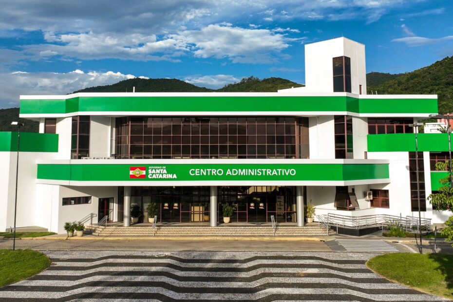 Profissionais celebram acordo de investimento com a cidade de Santa Catarina ao fundo, simbolizando a solidez fiscal do estado.