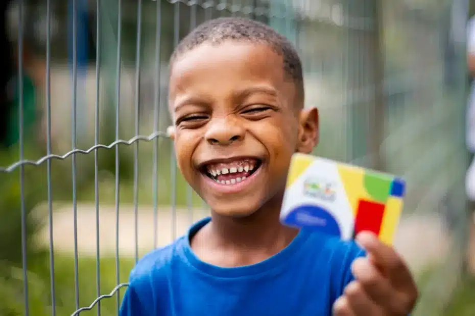 Mão segurando celular com app Bolsa Família e calendário de dezembro marcado