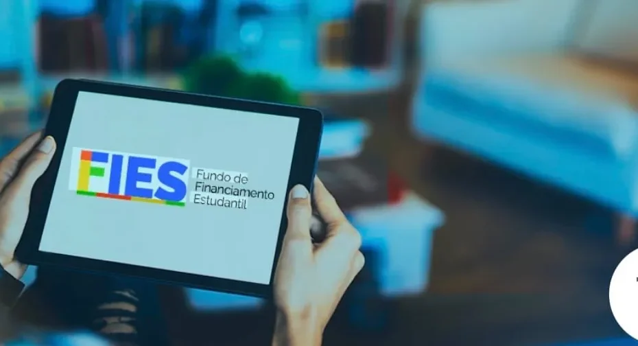Estudante atento complementando inscrição do Fies no laptop com documentos importantes.