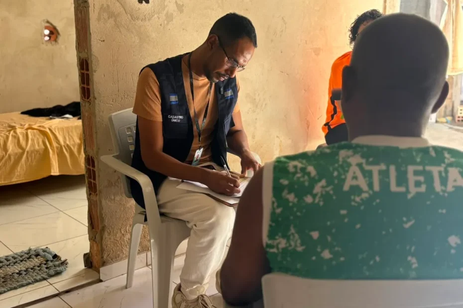 Pessoa preocupada ao receber visita domiciliar, observando crachá de identificação de um suposto entrevistador do Cadastro Único