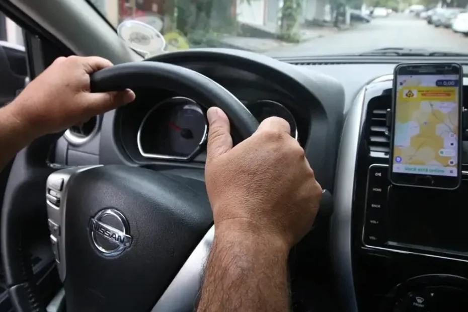 Motorista de aplicativo sorrindo e usando o celular dentro de um carro novo, representando o benefício financeiro.