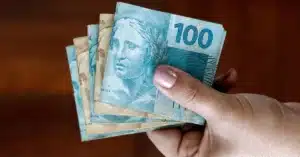 Aposentado segurando nota de real próximo a um calendário e telefone celular